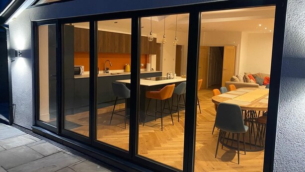 A modern kitchen with a central island, bar stools, and a dining area with a wooden table and chairs. - Best house on the street! Up to 10 guests- perfect for families, contractors (Coulsdon)