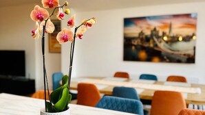 A modern interior with a dining area, a table with a tablet displaying a manual, and a potted orchid. - Best house on the street! Up to 10 guests- perfect for families, contractors (Coulsdon)
