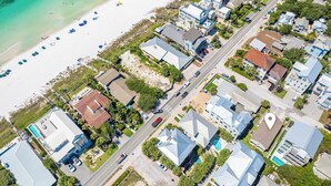 Vue aérienne d’une zone résidentielle côtière, avec des maisons, une plage et une route.