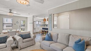 Un salon spacieux avec un grand canapé beige, une table basse et un coin repas à l’arrière-plan.
