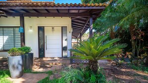 A house with a covered porch, a door with a number, and potted plants.
