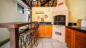 A kitchen with a brick oven, wooden cabinets, and a dining area with a table and chairs.