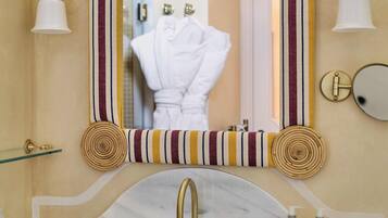 A bathroom with a striped vanity, a large mirror, and a gold faucet.