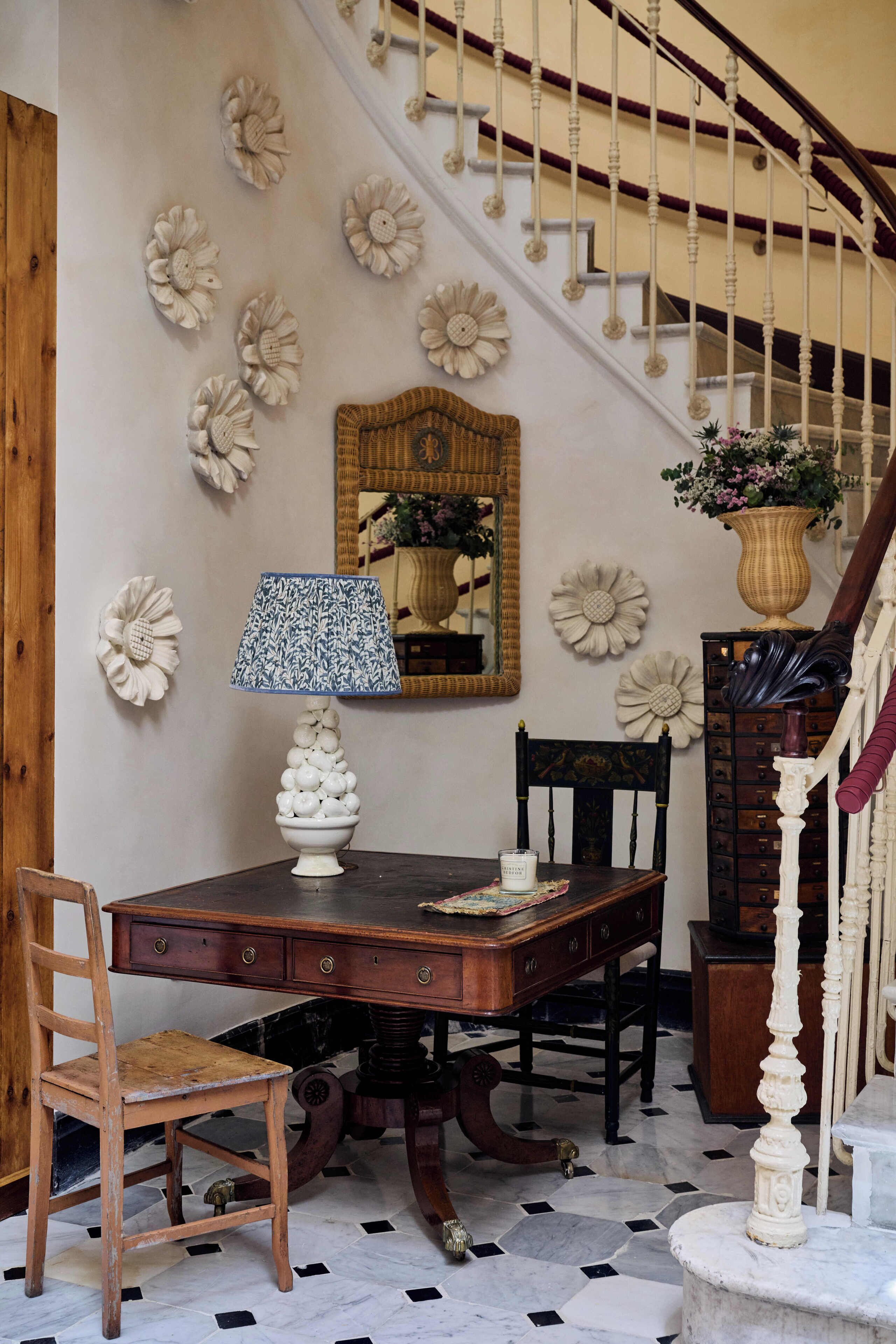 A dining area with a wooden table, chairs, a patterned table lamp, and decorative wall art.