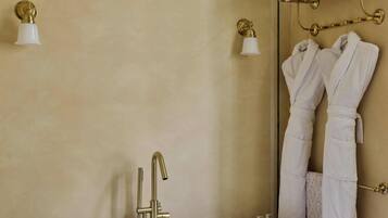 Un baño con una bañera independiente, un perchero con dos toallas blancas y dos lámparas fijadas a la pared.