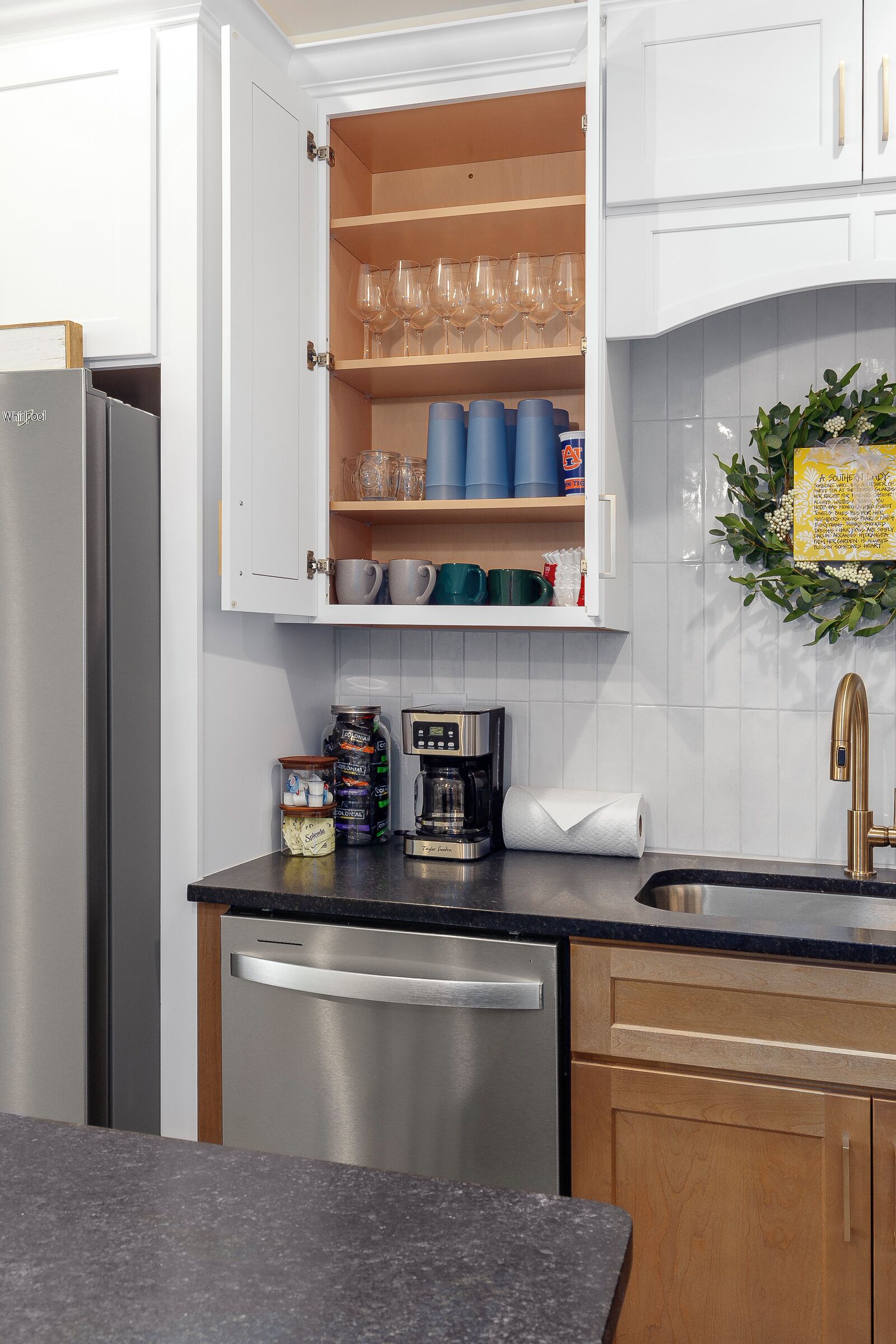 A kitchen with white cabinets, a stainless steel dishwasher, and a wooden countertop.