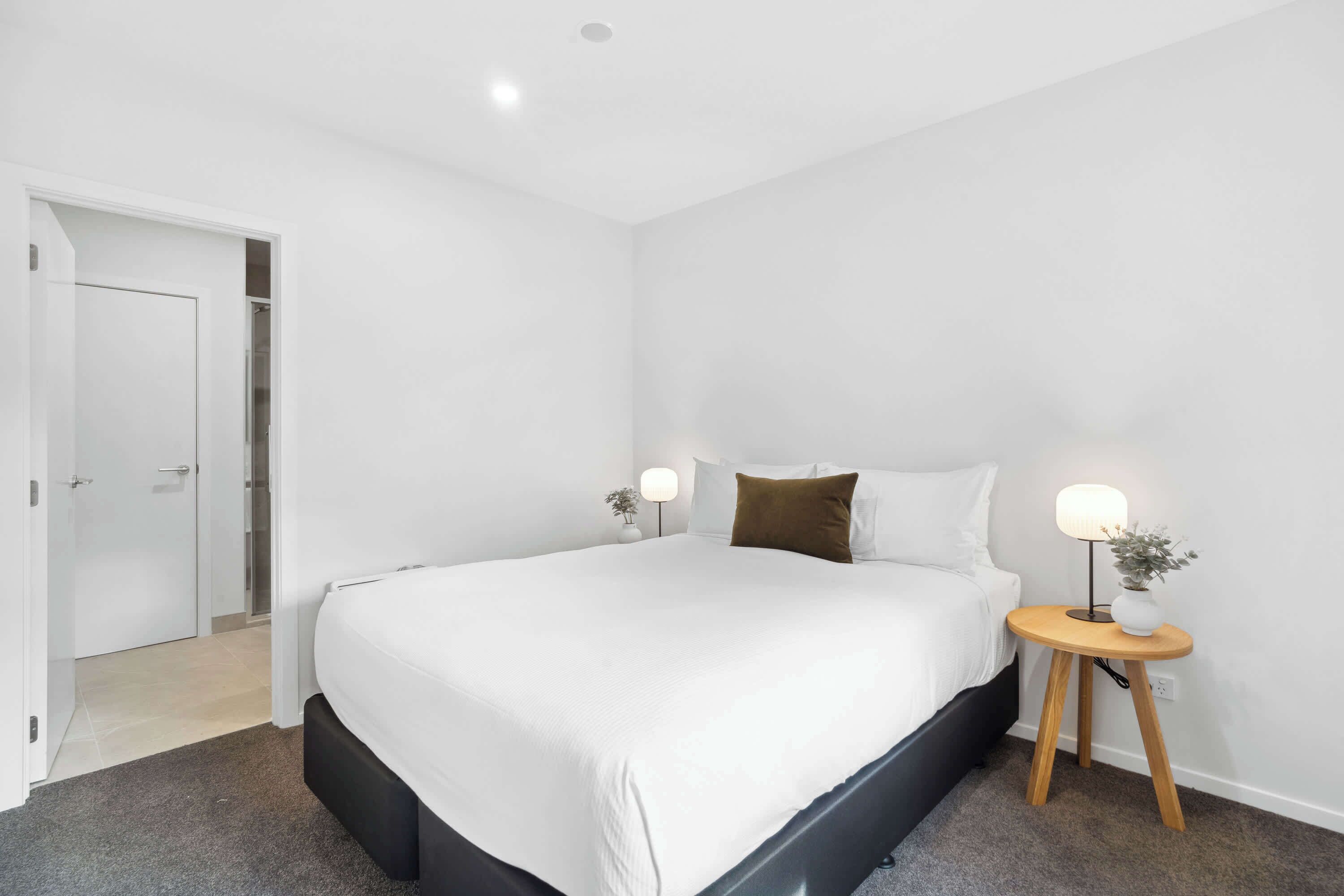 Une chambre moderne avec un grand lit, des lampes de chevet et une petite table sur laquelle est posée une plante.