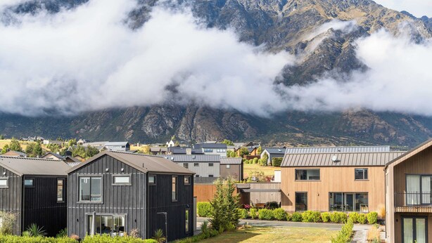 A modern building complex with a mountain backdrop.