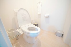 A modern bathroom with a white toilet, a bidet, and a small trash bin. - TRANSIT HOSTEL (Izumisano)