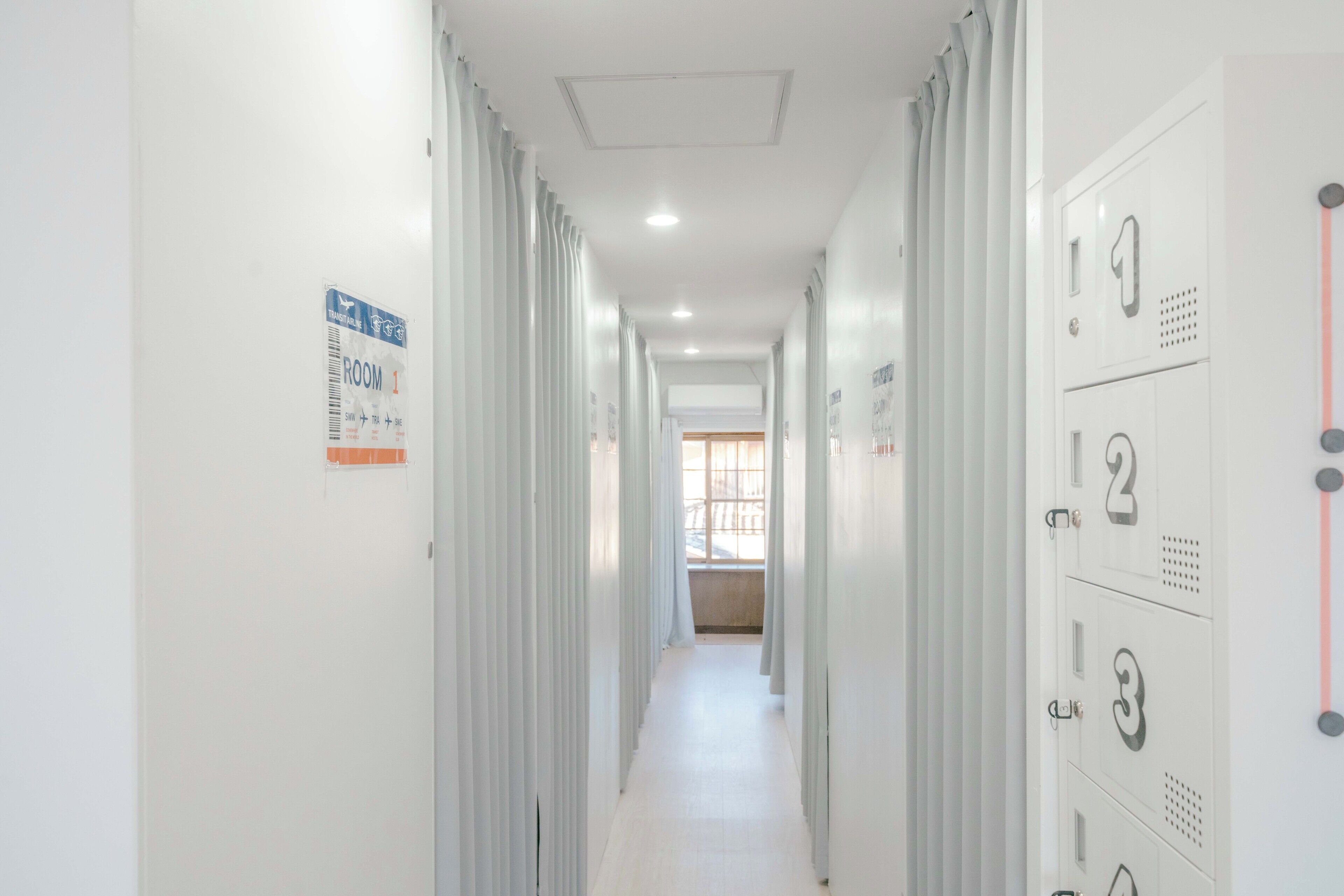 A corridor with lockers on one side and a door with a sign on the other.