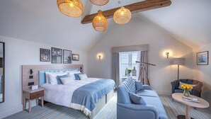A modern hotel room with a large bed, a sofa, a small table, and a balcony with a view. - The Ship Hotel (Leigh-on-Sea)