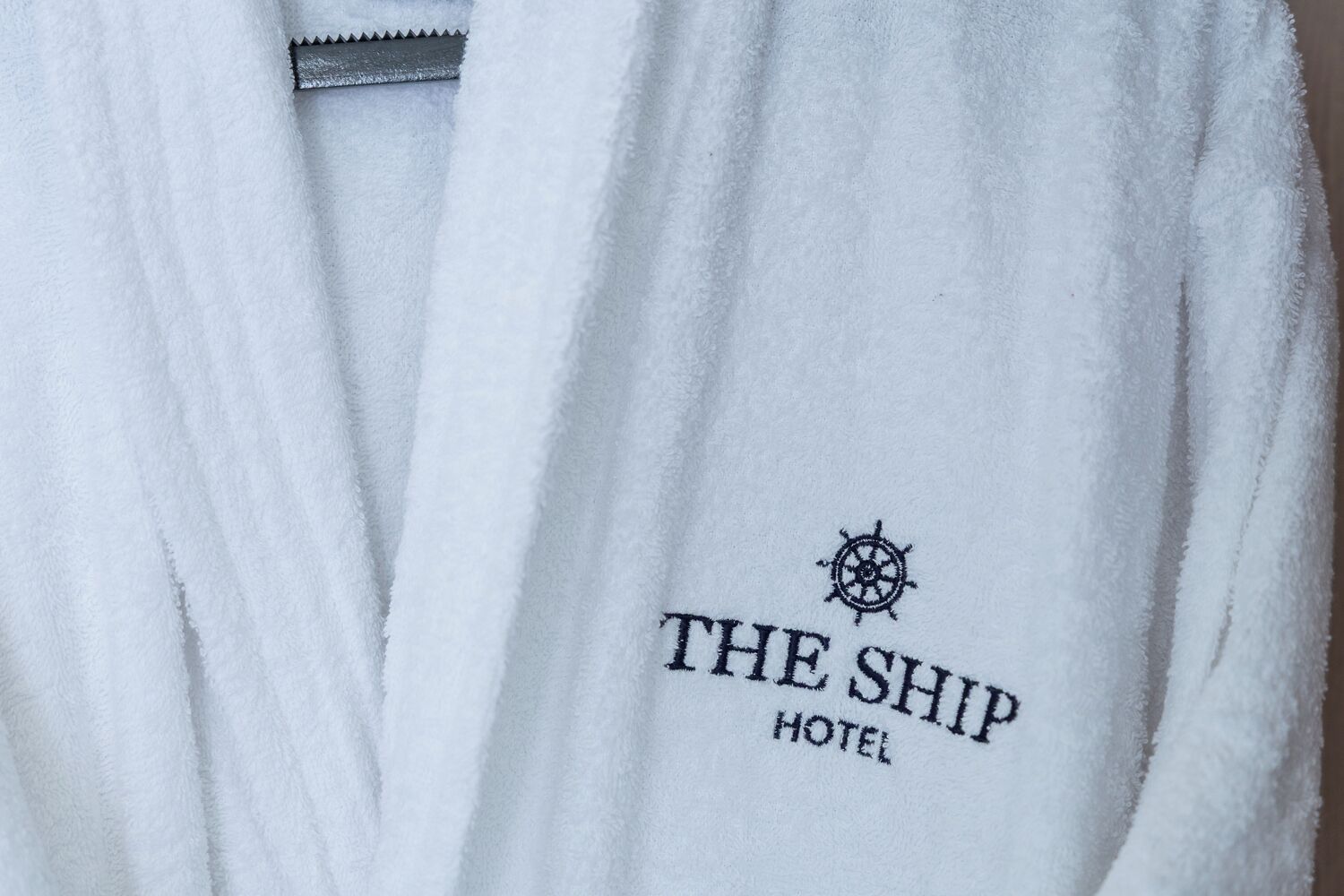 A white towel with "THE SHIP HOTEL" embroidered on it.