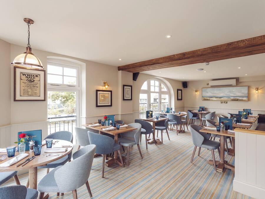 Un restaurant avec des tables rondes, des chaises bleues et un sol à rayures.