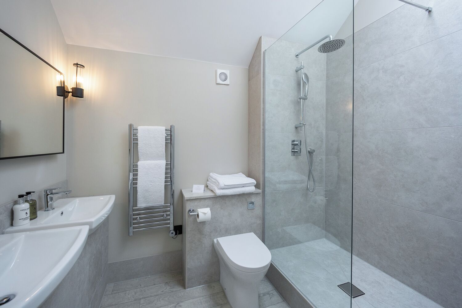 Een moderne badkamer met een douchecabine van glas, een witte wastafel en een toilet.