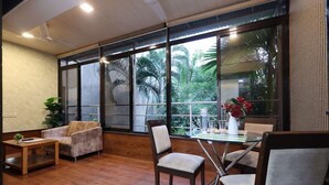 A spacious room with large windows, a wooden floor, a sofa, two chairs, and a small table.