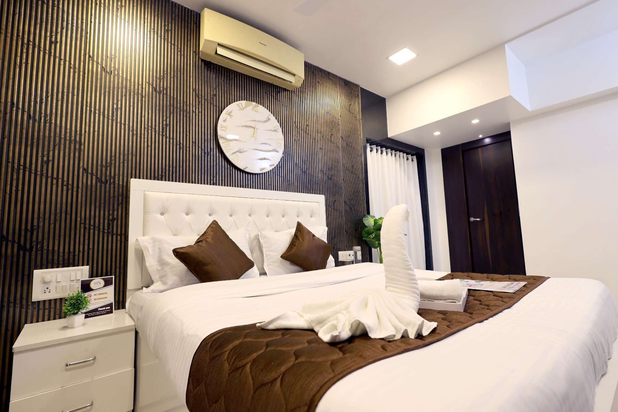 Een moderne hotelkamer met een groot bed, een wit hoofdbord en een wandairconditioner.