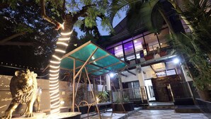 A courtyard with a lion statue, a covered seating area, and a checkered floor.