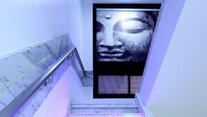 A marble staircase with purple lighting, leading to a room with a large wall-mounted artwork.