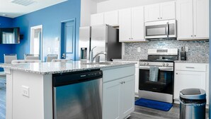 A modern kitchen with white cabinets, stainless steel appliances, and a blue accent wall. - 3BR/2.5 Bath Townhome Golf Sim, Theatre by NMB Sport Complex (Little River)