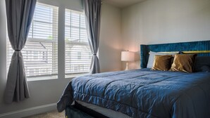 A bedroom with a large bed, a bedside table, a lamp, and a view through the window. - 3BR/2.5 Bath Townhome Golf Sim, Theatre by NMB Sport Complex (Little River)