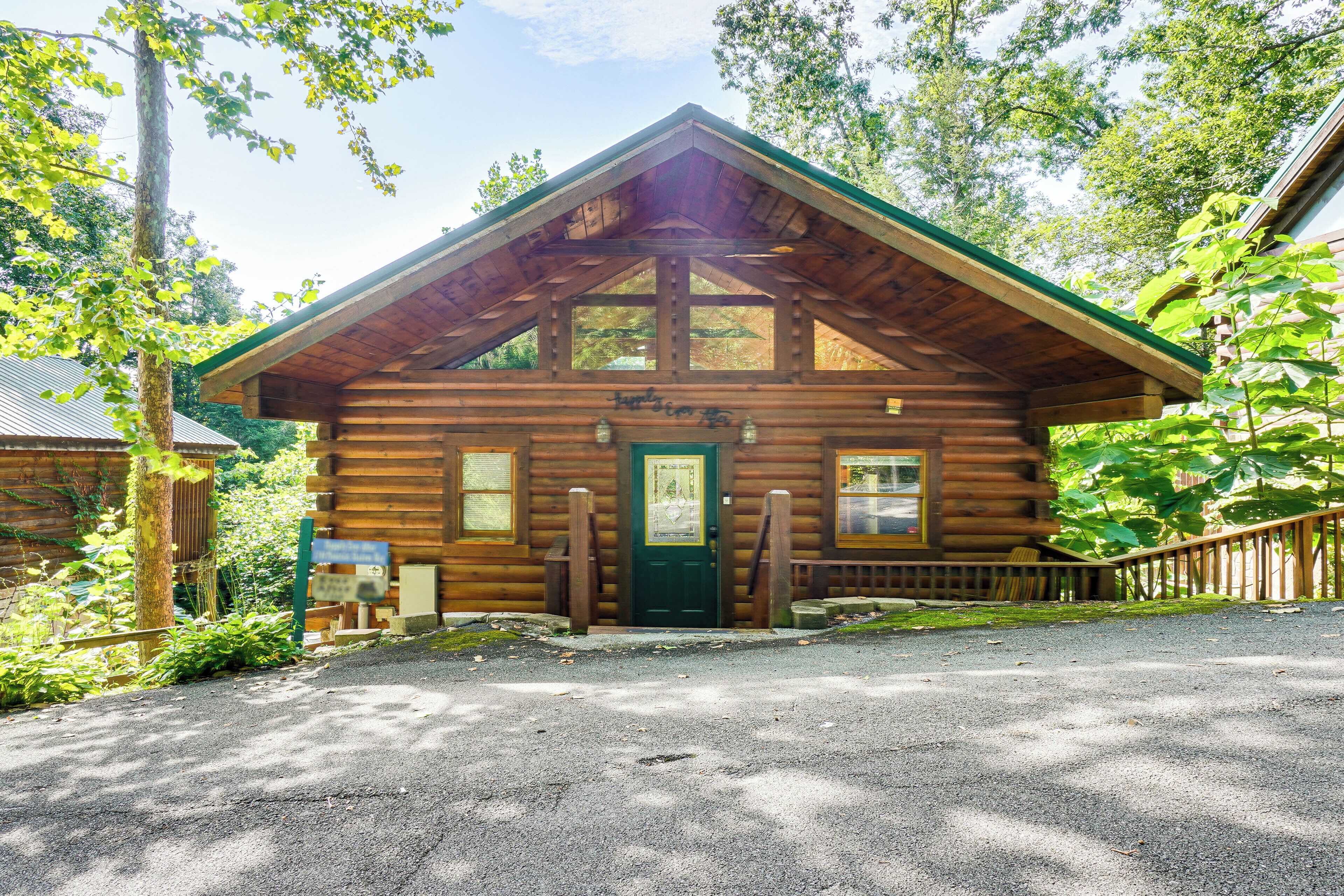 Eine Blockhütte mit grüner Tür, Holzgeländern und einer Schotterzufahrt.