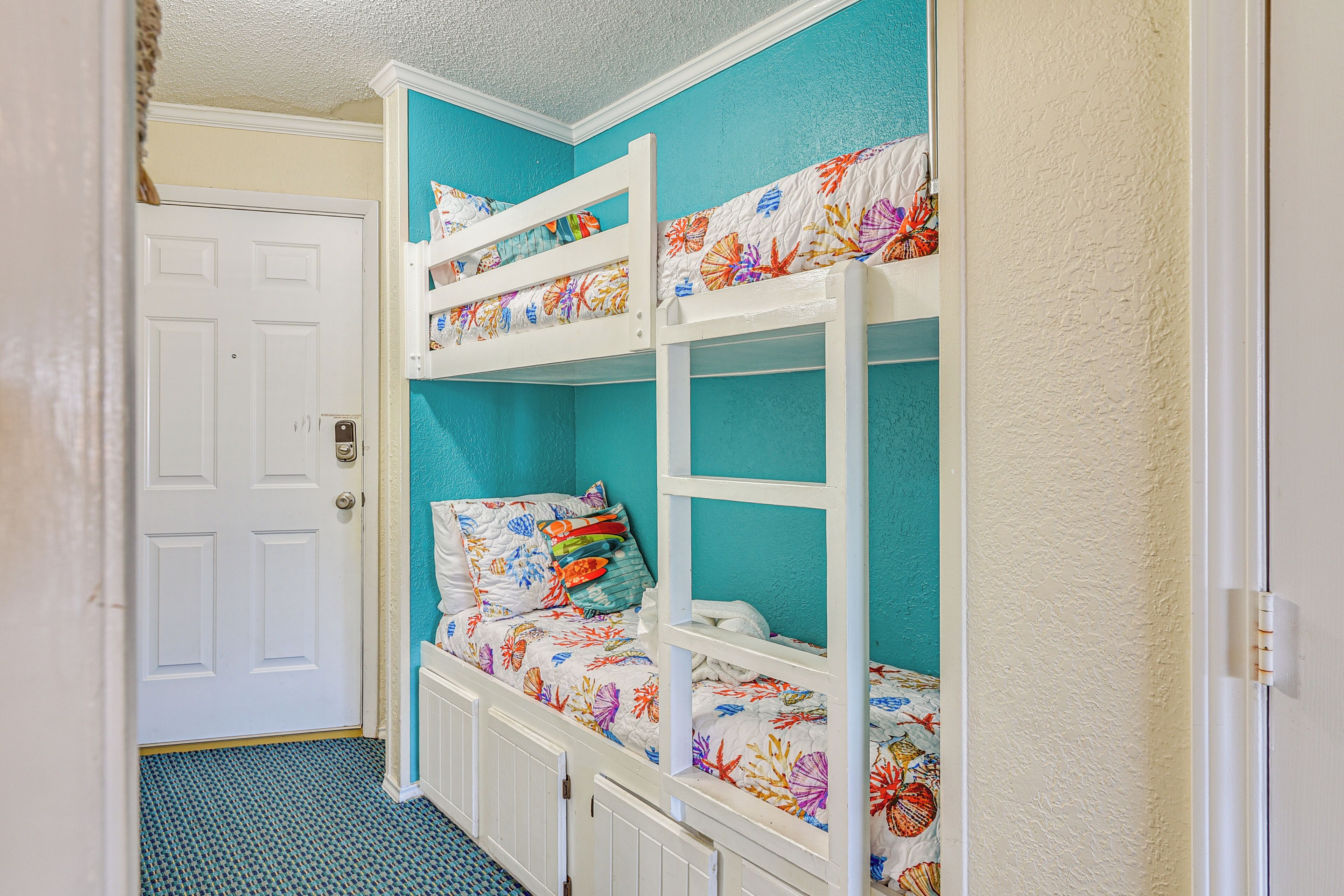 A bunk bed with a floral bedspread and a white door in the background.