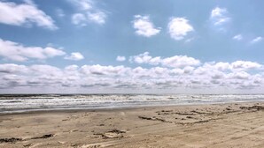 Une plage avec un ciel dégagé et des vagues.