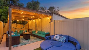 An outdoor patio with a covered seating area, a hammock, and a fire pit.