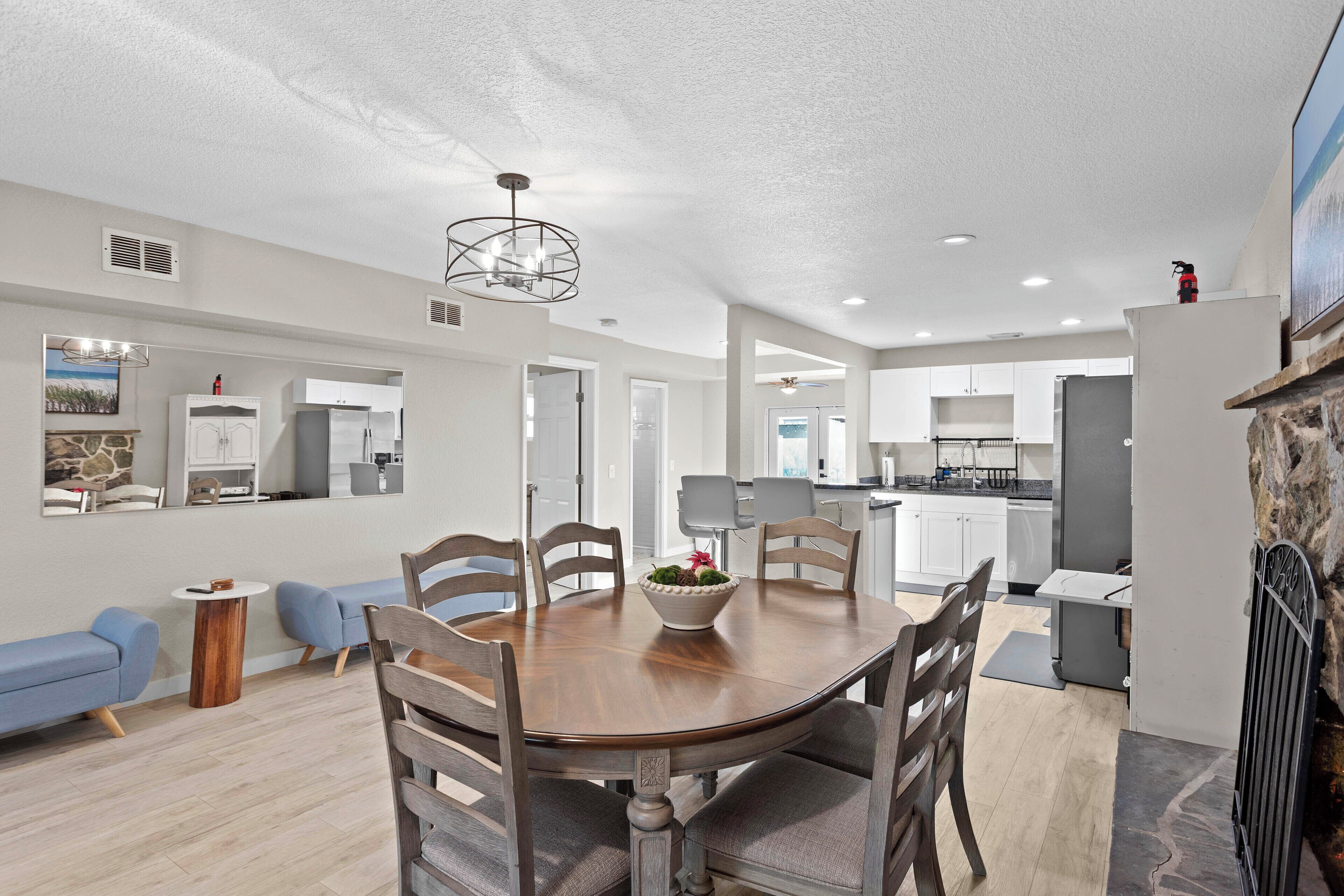 A spacious living room with a wooden dining table, blue sofas, and a stone fireplace.