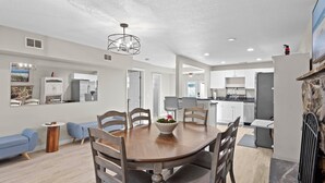 A spacious living room with a wooden dining table, blue sofas, and a stone fireplace.