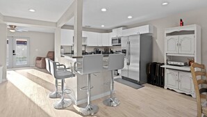 A modern kitchen with white cabinets, stainless steel appliances, and a central island with bar stools.