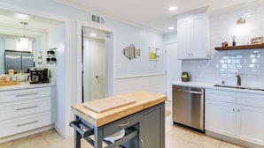 A modern kitchen with white cabinets, stainless steel appliances, and a wooden countertop. - Beachfront Retreat w/ Pool Access in Gulf Shores! (Gulf Shores)