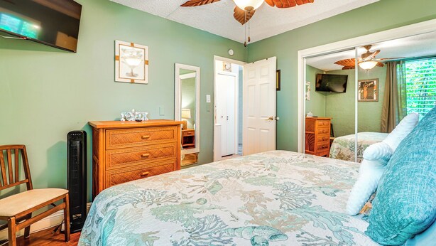 Un dormitorio con cama, cómoda, silla y ventilador de techo.