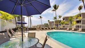 A poolside area with lounge chairs, a glass table, and umbrellas. - 2 Mi to Town: Oceanside Kailua-kona Paradise! (Kailua-Kona)
