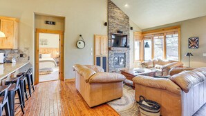 A spacious living area with a stone fireplace, leather sofas, and a wooden floor. - Mountain-view Cabin Near Trails in Powell Butte! (Powell Butte)