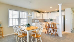 A modern kitchen with white cabinets, a wooden dining table, and chairs. - Walk to Beach: Wildwood Apt w/ Balcony! (Wildwood)