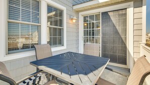 A patio with a table and chairs, a sliding glass door, and a window with blinds. - Half-mi to Wildwood Boardwalk: Family-friendly Apt (Wildwood)