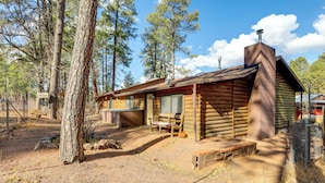 A rustic log cabin with a chimney, a porch with a table and chairs, and a fenced yard. - 16 Mi to Mogollon Rim: Home w/ Deck in Payson! (Payson)