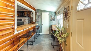 A wooden bar area with stools, a stone fireplace, and a door with a flower decoration. - 16 Mi to Mogollon Rim: Home w/ Deck in Payson! (Payson)