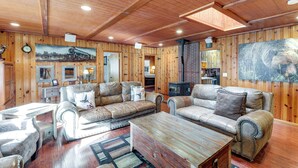 A cozy cabin interior with wooden walls, leather sofas, a fireplace, and a large bear painting. - 16 Mi to Mogollon Rim: Home w/ Deck in Payson! (Payson)