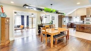 Een ruime keuken met houten kastjes, een eethoek met een houten tafel en stoelen, en een groot raam dat zorgt voor natuurlijk licht.