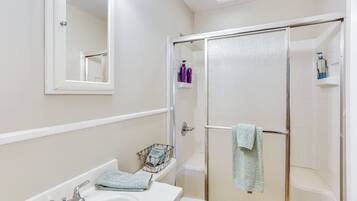 A bathroom with a white sink, a mirror, a glass-enclosed shower, and a towel rack.