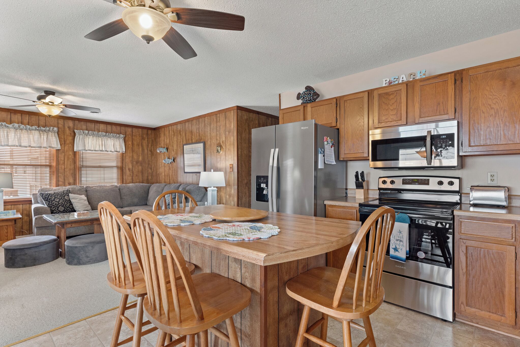 A modern kitchen with wooden cabinets, stainless steel appliances, and a dining area with wooden chairs and a table.