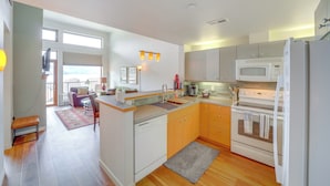 Cocina moderna equipada con lavavajillas, horno y microondas. Cuenta con una zona de comedor con banco y alfombra.