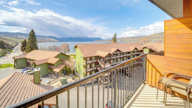 Un hotel con balcón que da a un lago y montañas.