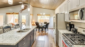 A kitchen with a granite countertop, stainless steel appliances, and a dining area with a table and chairs. - Hot Tub & Outdoor Living: Relaxing Show Low Cabin (Show Low)