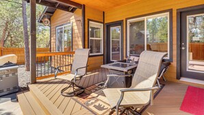 A covered deck with outdoor seating, a grill, and large windows. - Hot Tub & Outdoor Living: Relaxing Show Low Cabin (Show Low)
