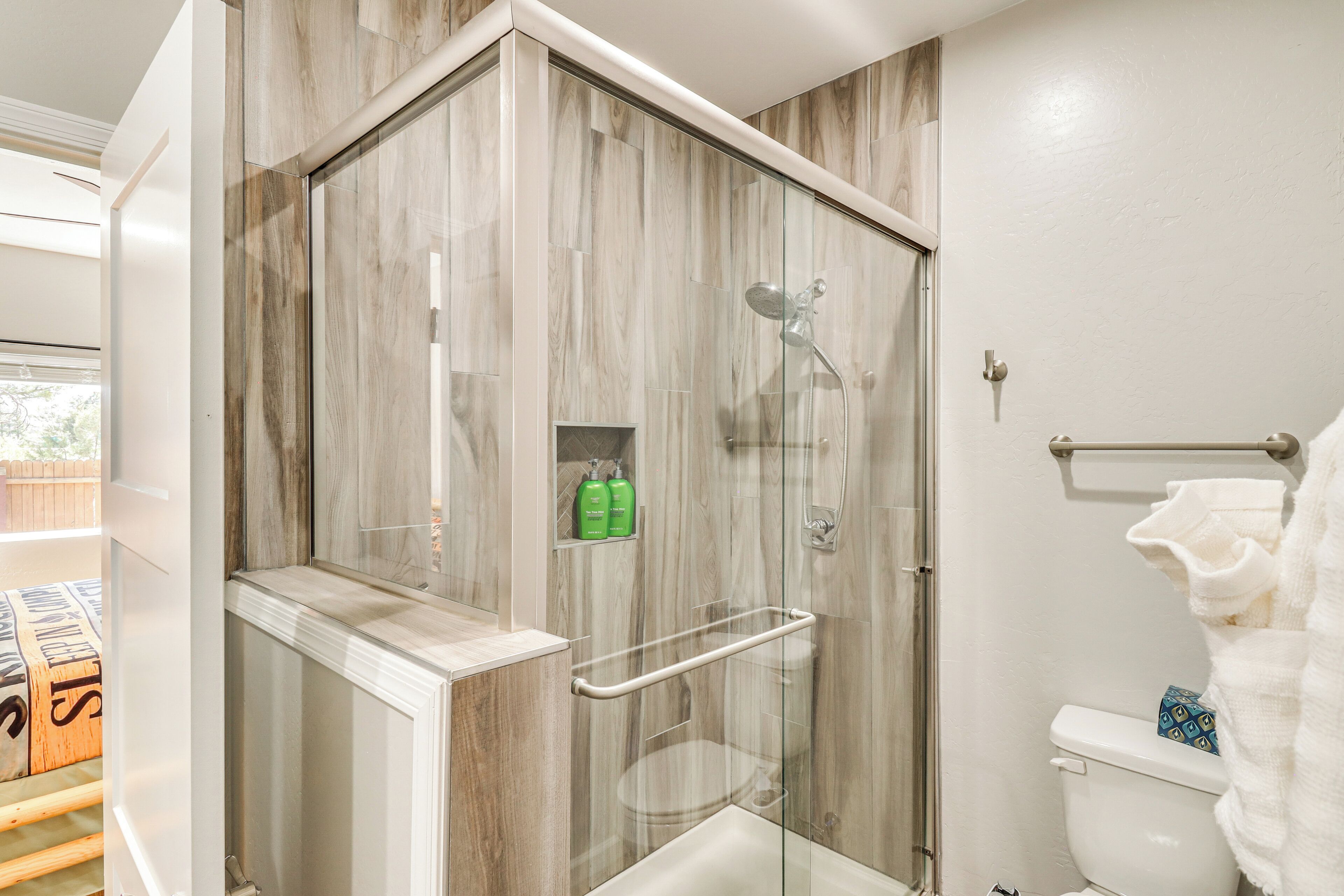A modern bathroom with a glass-enclosed shower, a white toilet, and a glass door.