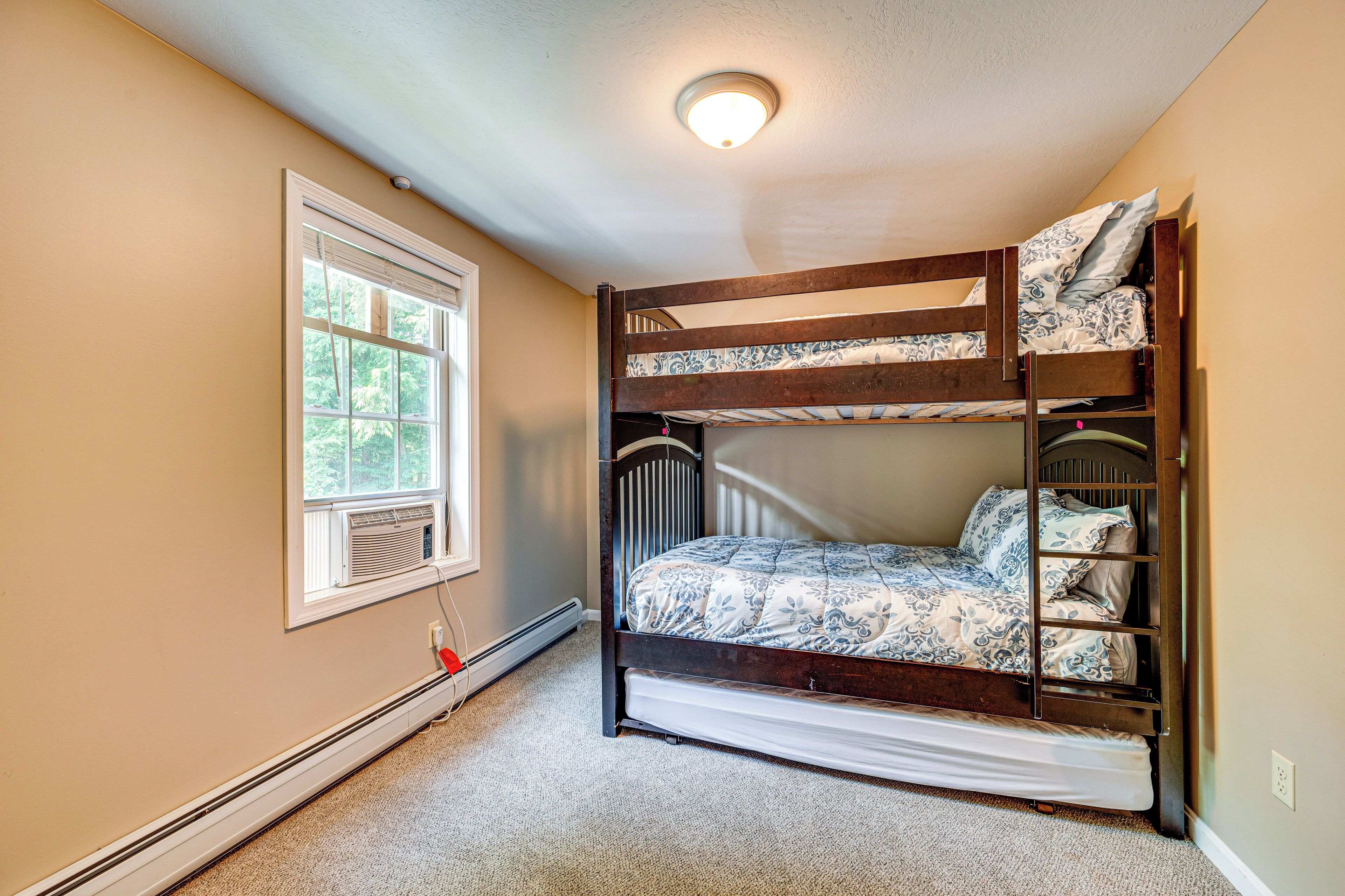 A bunk bed in a room with beige walls, a window, and a ceiling light.
