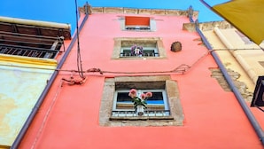 Un edificio de fachada roja, con múltiples ventanas y balcones adornados con arreglos florales.